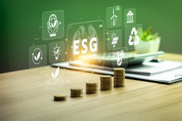 Cinco pilhas de moedas, uma calculadora e uma prancheta junto de uma série de ícones digitais que falam sobre ESG, mostrando a união entre ESG e contábeis